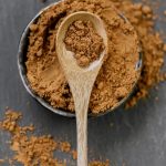 Guarana powder in a wooden spoon in a cup on a black slate background.Natural tonic. Alternative medicine and homeopathy.Supplements and vitamins. Healthy eating. sports nutrition.